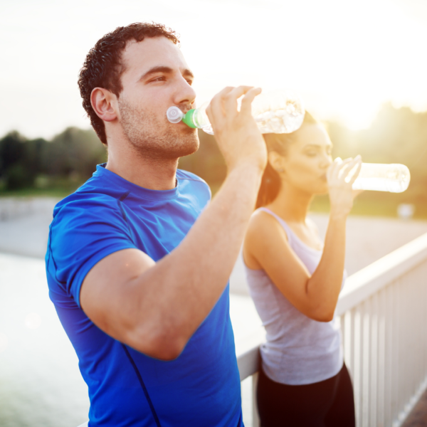 Imagen de una pareja de deportistas hidratándose tomando agua en el medio de su entrenamiento deportivo de running.