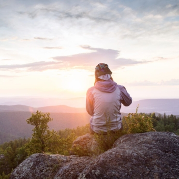 Imagen de un deportista mirando al horizonte con montañas detrás y bosque. Se lo ve contemplando y pensando cómo mejorar su rendimiento, cómo no sentir estrés, presión y analizando si el mindfulness puede ayudarlo.